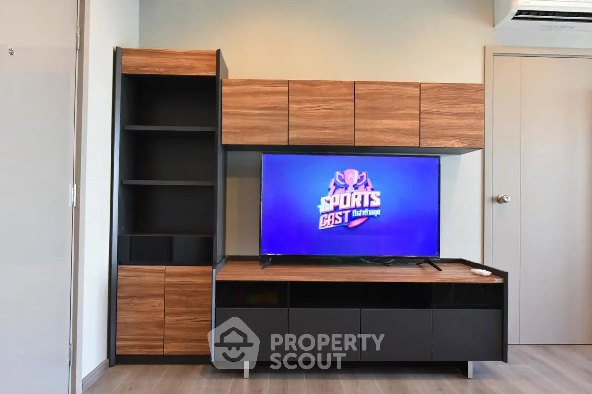 Modern living room with sleek wooden and black entertainment unit and mounted TV.