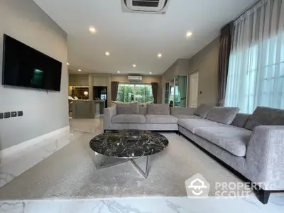 Spacious living room with plush sofas, marble flooring, and an open layout leading to a modern kitchen, perfect for entertaining.