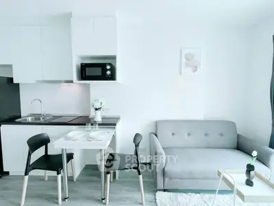 Modern living room with sleek kitchen and cozy dining area, featuring minimalist decor and natural light.