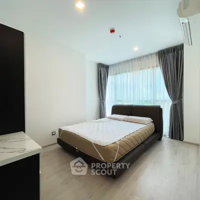 Spacious bedroom with modern design and large window for natural light.