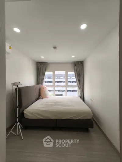 Cozy bedroom with large window and modern decor in a stylish apartment.