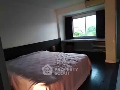Cozy bedroom with large window and natural light, featuring a comfortable bed and minimalist decor.