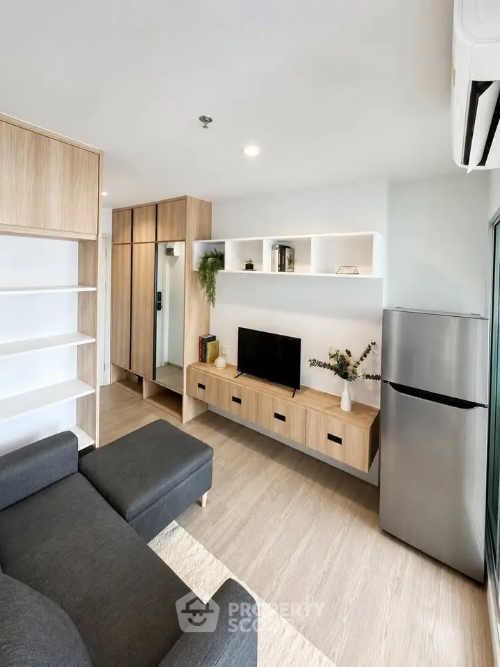 Modern living room with sleek furniture and stainless steel fridge, perfect for urban living.