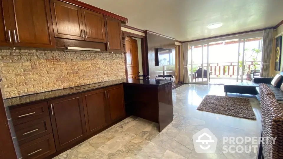 Spacious living room with elegant wooden cabinets and marble flooring, opening to a large balcony with scenic views.