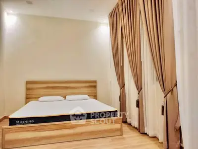 Spacious bedroom with elegant curtains and wooden flooring, featuring a comfortable bed for a cozy retreat.