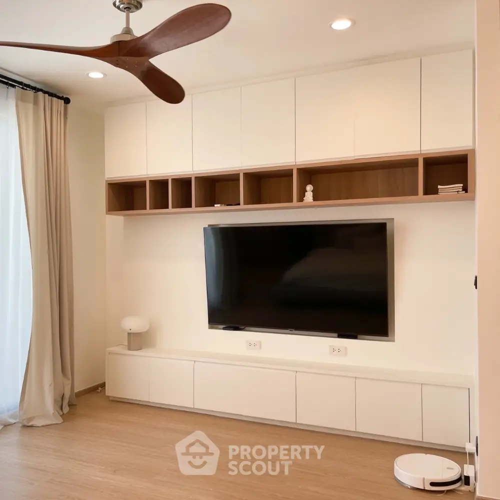 Modern living room with built-in entertainment center and sleek ceiling fan