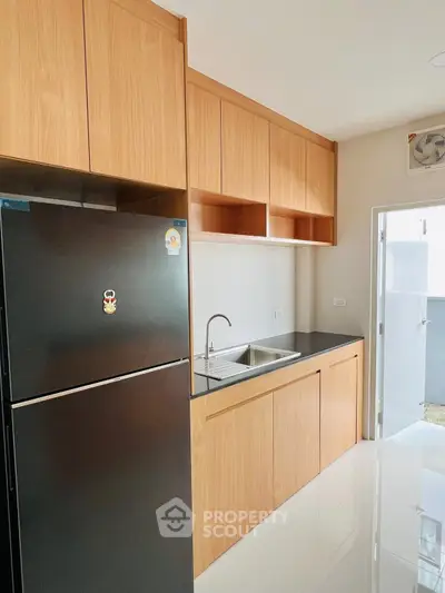 Modern kitchen with sleek black fridge and wooden cabinets