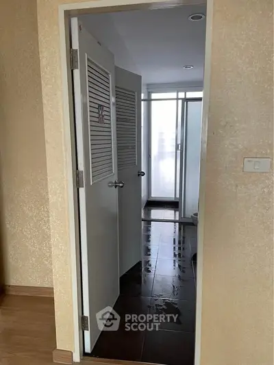 Interior view of a hallway leading to a bathroom with wet floor tiles, showcasing modern design.