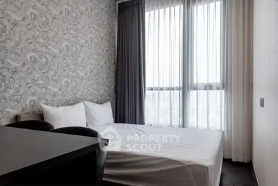 Modern bedroom with stylish wallpaper and large window for natural light.