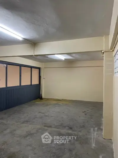 Spacious empty storage room with concrete floor and fluorescent lighting.