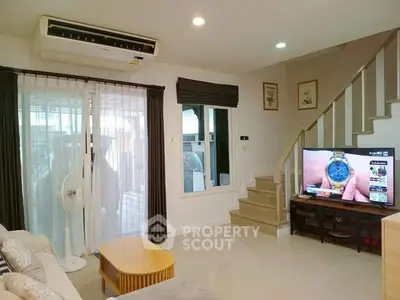 Cozy living room with modern decor, featuring a staircase and large window for natural light.