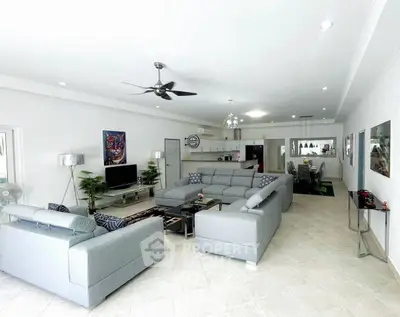 Spacious modern living room with sleek gray sofas and open kitchen layout.