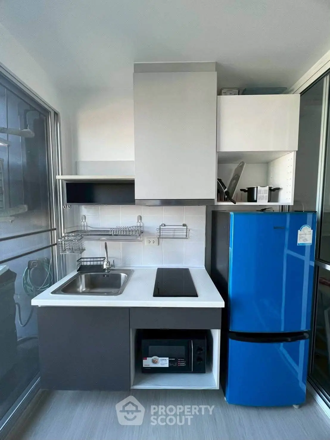Modern compact kitchen with sleek cabinetry and vibrant blue fridge, perfect for urban living.