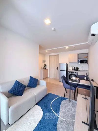 Modern living room with stylish furniture and compact kitchen in open layout apartment.