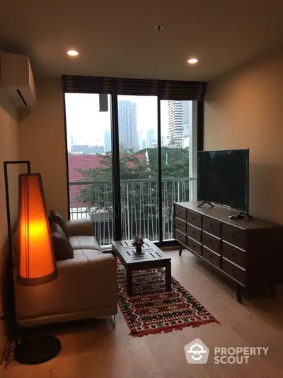 Cozy living room with warm lighting, floor-to-ceiling windows offering a city view, modern furnishings, and a welcoming ambiance perfect for relaxation or entertaining guests.