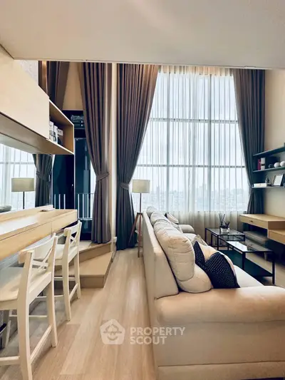 Modern living room with high ceilings and large windows offering city views.