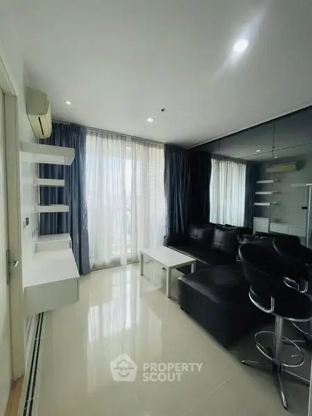 Modern living room with sleek furniture and large windows offering natural light.