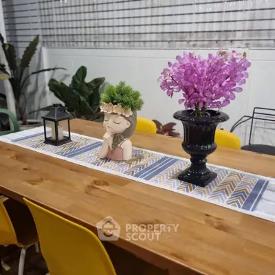 Charming dining area with wooden table, vibrant chairs, and elegant floral centerpiece.