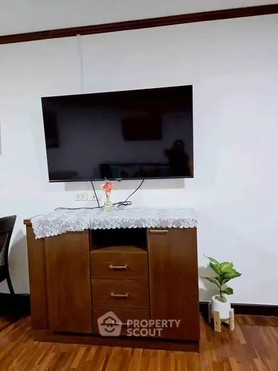 Cozy living room with mounted TV and elegant wooden cabinet on polished floor.