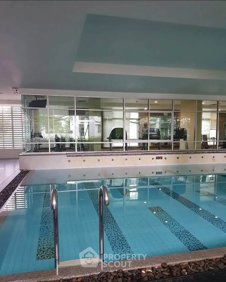 Luxurious indoor swimming pool with modern design and glass walls in a high-end residential building.