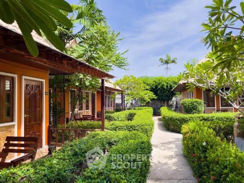 Charming garden pathway leading to cozy bungalow-style homes with lush greenery.
