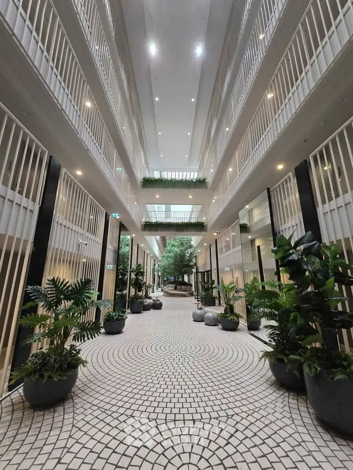 Luxurious modern building entrance with elegant design and lush greenery, perfect for upscale living.