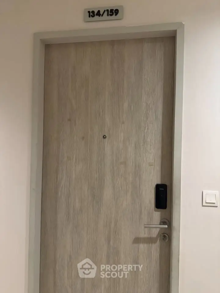Modern apartment door with electronic lock and room number, showcasing secure entryway.