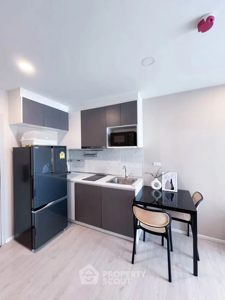 Modern kitchen with sleek cabinetry, dining area, and appliances in a stylish apartment.