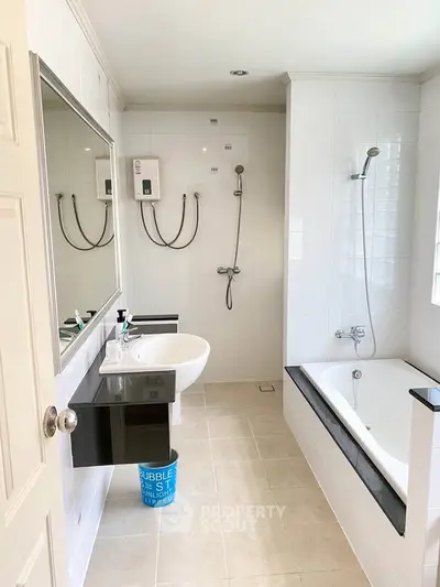 Spacious modern bathroom with bathtub and sleek fixtures in a bright, tiled setting.