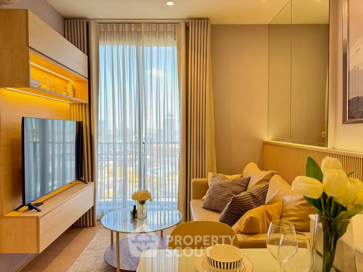 Modern living room with elegant decor, large TV, and city view through sheer curtains.