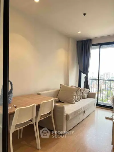 Modern living room with cozy sofa and dining area, featuring a balcony with city view.