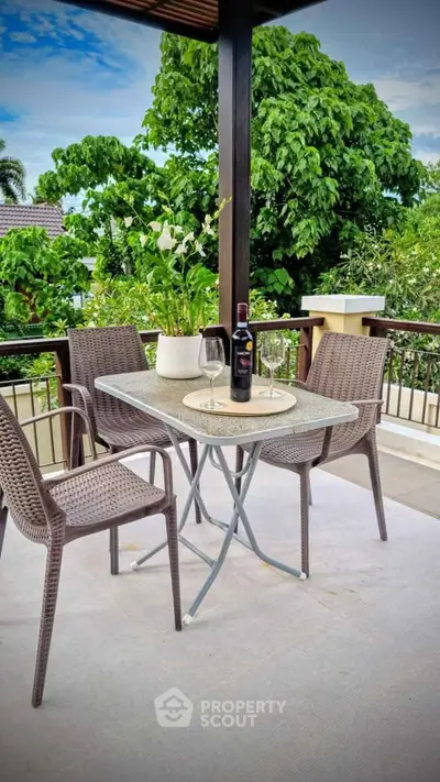 Charming balcony with outdoor seating and lush greenery view, perfect for relaxation and entertaining.