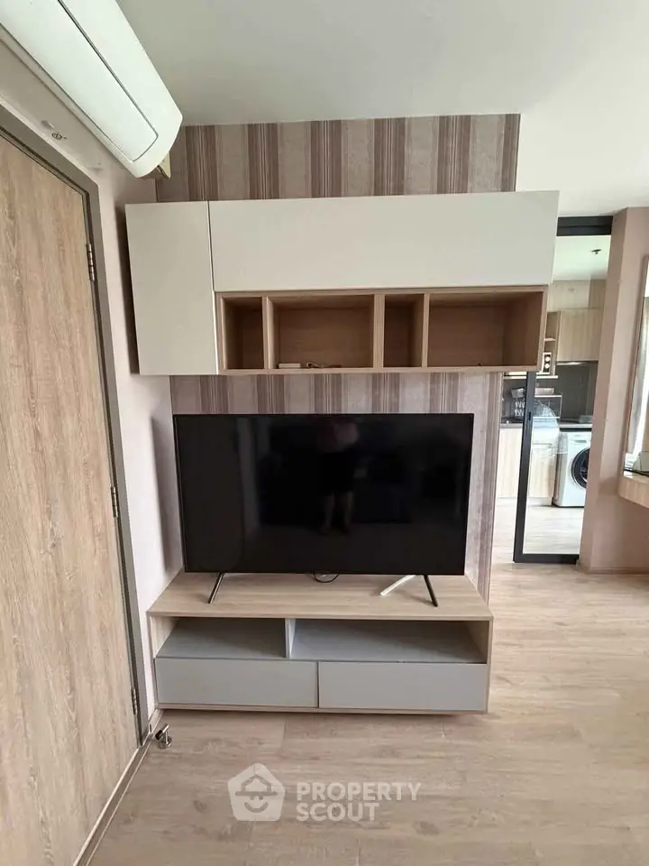 Modern living room with sleek TV stand and wall-mounted storage, featuring stylish wood flooring and contemporary decor.