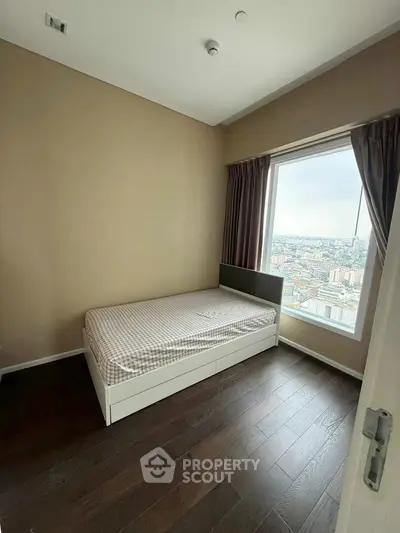 Cozy bedroom with single bed and stunning city view from large window.