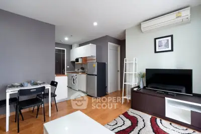 Modern open-plan living room with kitchen, featuring stylish decor and appliances.
