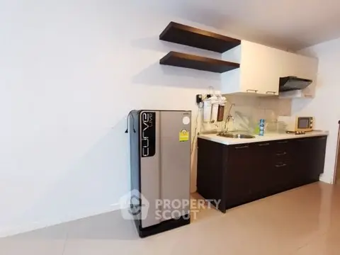 Modern kitchen with sleek cabinets and compact fridge in a stylish apartment.