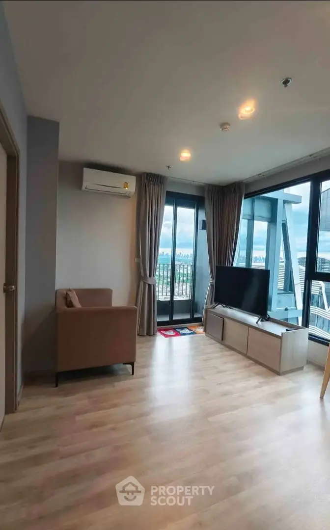 Spacious living room with large windows offering stunning city views, modern furnishings, and natural light.