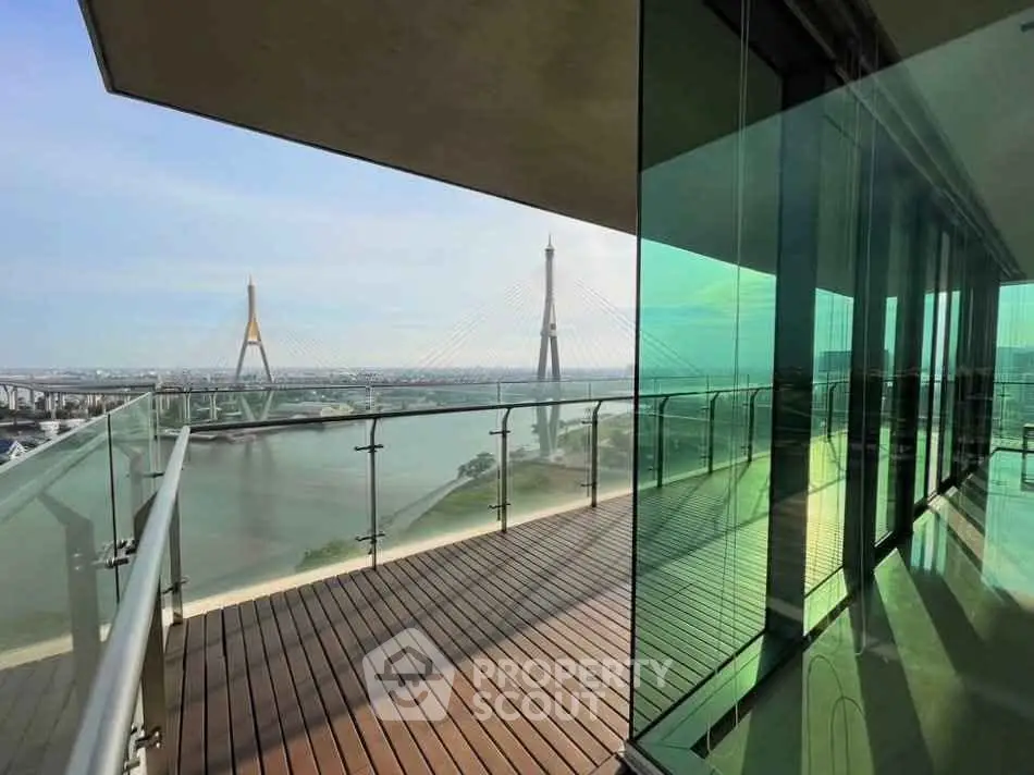 Stunning high-rise balcony with panoramic river and bridge view, featuring sleek glass railings and modern design.