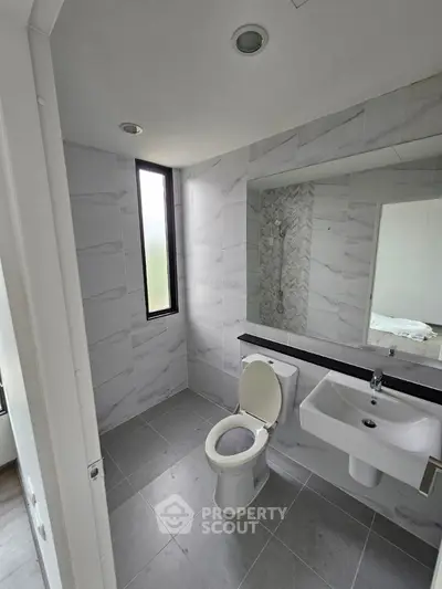 Modern bathroom with sleek tiles and large window for natural light.