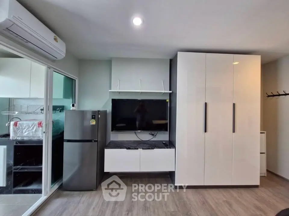 Modern studio apartment with sleek wardrobe and stainless steel fridge, featuring a minimalist design and ample storage.