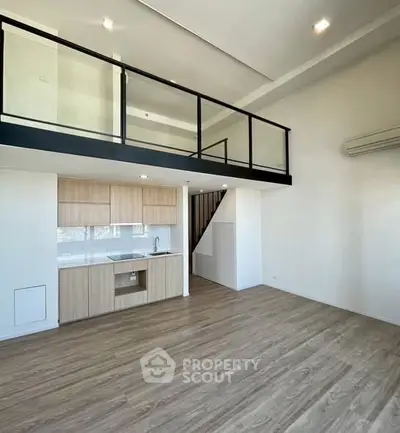Modern loft apartment with open kitchen and mezzanine, featuring sleek wooden flooring and minimalist design.