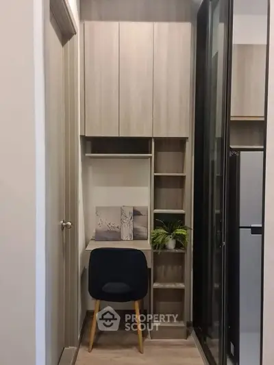 Modern compact study nook with sleek wooden cabinetry and stylish chair in a cozy apartment.