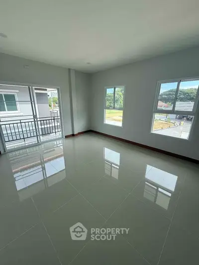 Spacious empty room with large windows and glossy tiled floor, offering abundant natural light and outdoor views.
