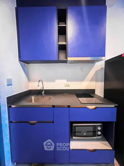 Modern compact kitchen with blue cabinets and built-in microwave