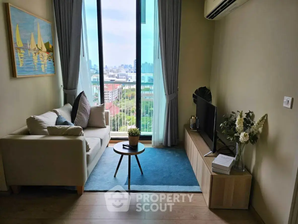 Cozy living room with large window offering stunning city view, modern decor, and natural light.