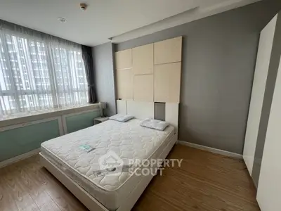 Spacious bedroom with large window and modern decor in a high-rise apartment.