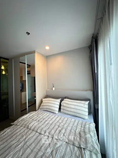 Cozy bedroom with striped bedding and natural light from large window