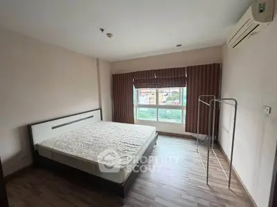 Spacious bedroom with large window and air conditioning in modern apartment.