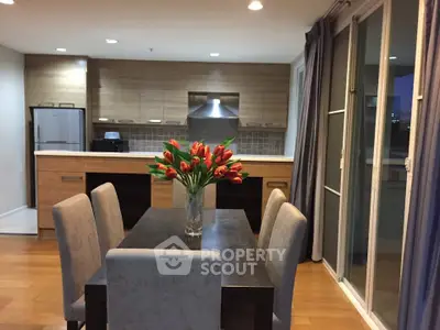 Modern kitchen and dining area with sleek wooden cabinets and elegant dining table.