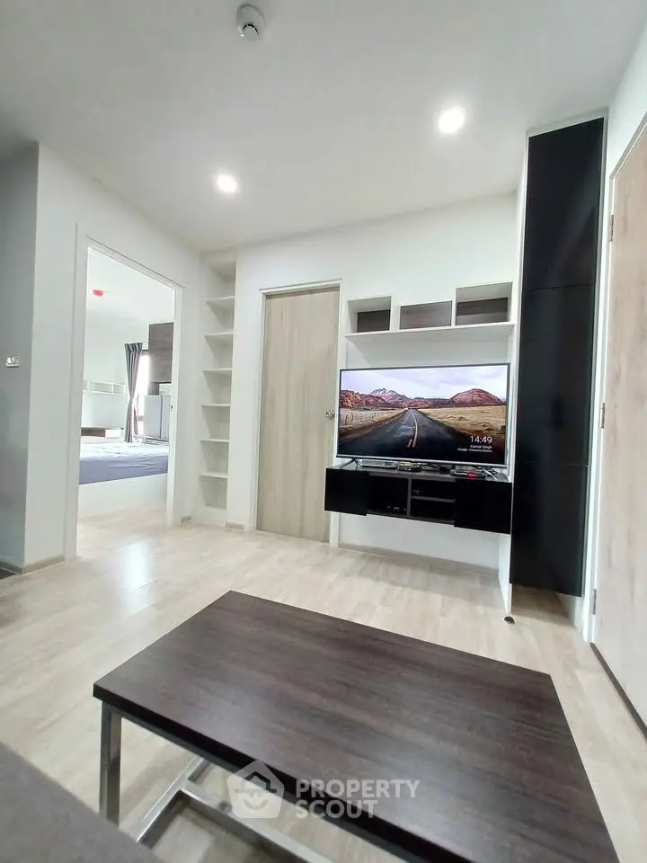 Modern living room with sleek furniture and built-in TV unit, showcasing minimalist design and open layout.